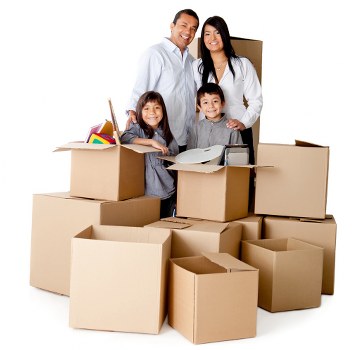 A family of four, consisting of a man, woman, and two children, standing inside a room filled with open cardboard moving boxes. The boxes are various sizes, some stacked or placed side by side, with a mix of closed and partially open containers revealing household items such as colorful plastic toys, a cordless phone, and kitchen utensils. The family is smiling and appears to be in the process of packing or unpacking, indicating a house move. The room is well-lit with natural or artificial light, and the background suggests an indoor residential setting, consistent with a typical home environment in Hackney or nearby areas. The scene emphasizes the practical aspects of house removals, which Hackney Man with Van services frequently facilitate, with a focus on household packing and moving preparations.